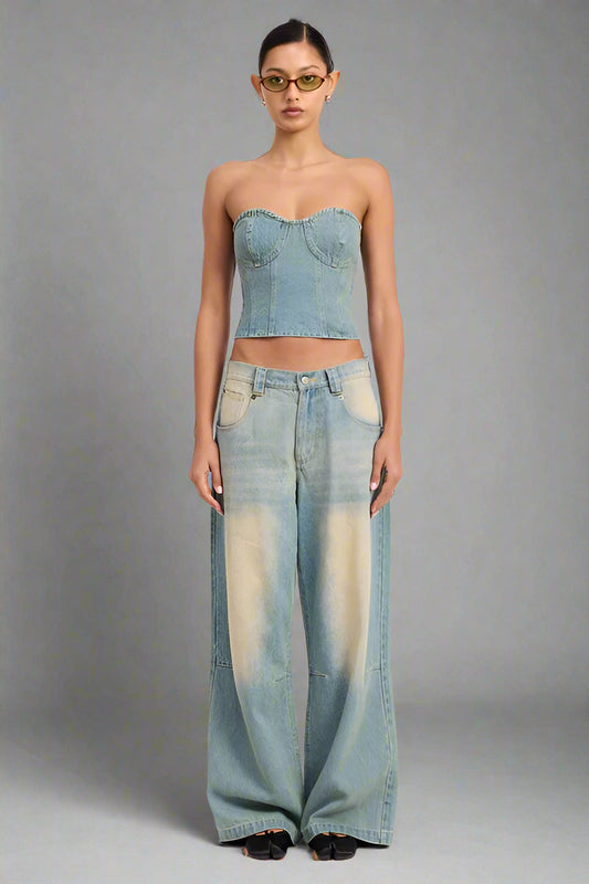 Woman wearing a denim strapless top and wide-leg jeans on a white background