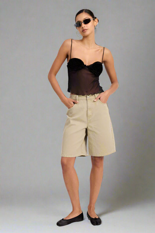 Woman wearing a black top and beige shorts on a white background
