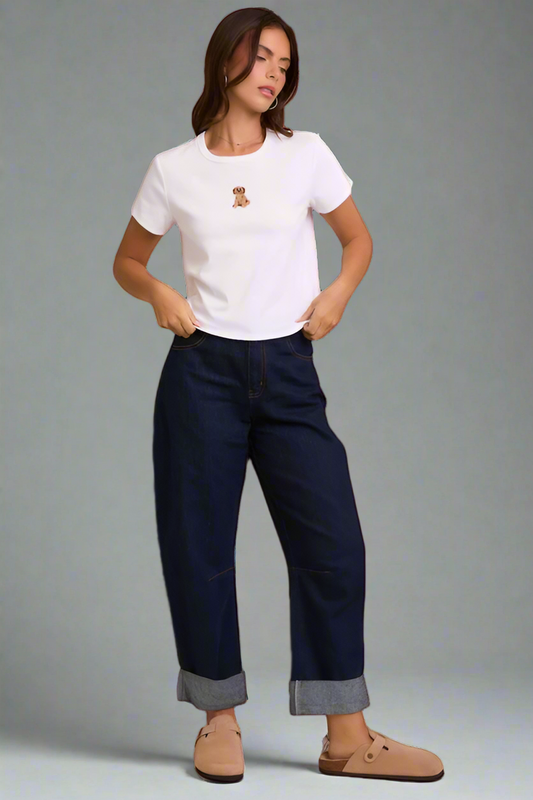 Woman wearing a white t-shirt with a small logo and dark blue jeans on a neutral background