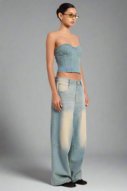 Woman wearing a denim strapless top and wide-leg jeans on a white background