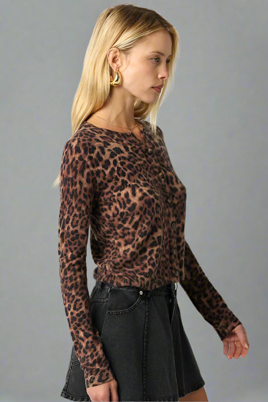 Woman wearing a leopard print long-sleeve top and black skirt on a neutral background