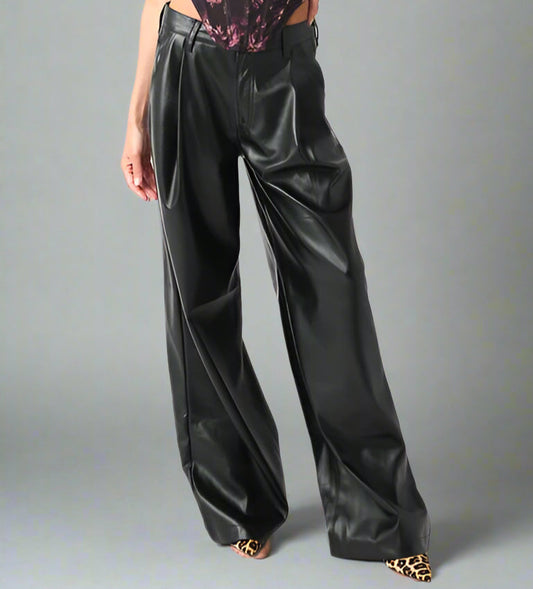 Woman wearing a floral tank top and black pants on a neutral background