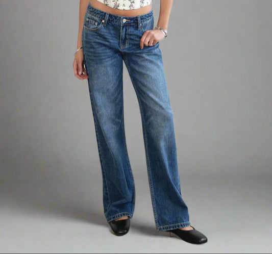 Woman wearing a floral top and blue jeans against a white background